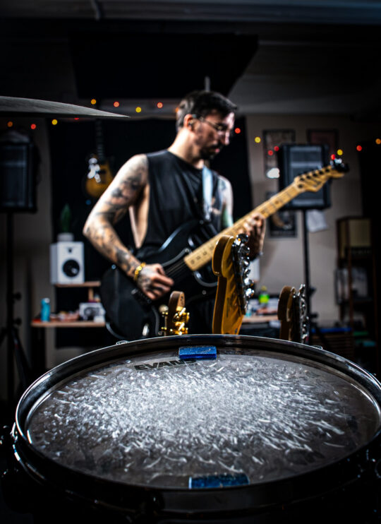 Drum set view of man playing electric guitar