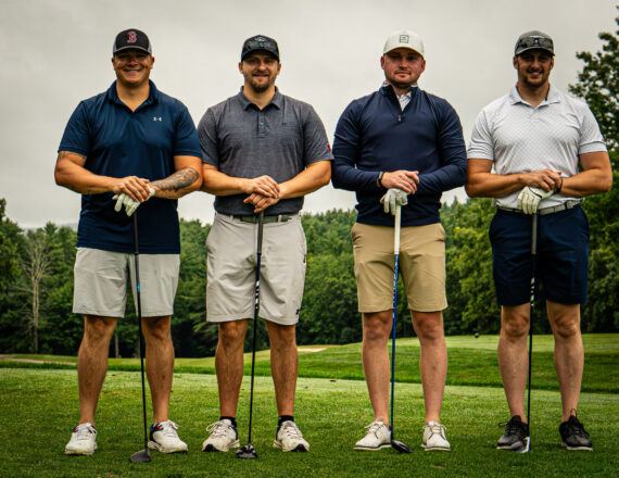 Four male golfers standing on a golf course holding their golf clubs
