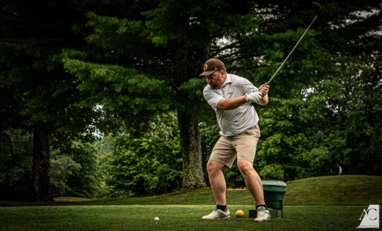Man playing golf outside swinging the golf club
