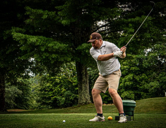 Man playing golf outside swinging the golf club