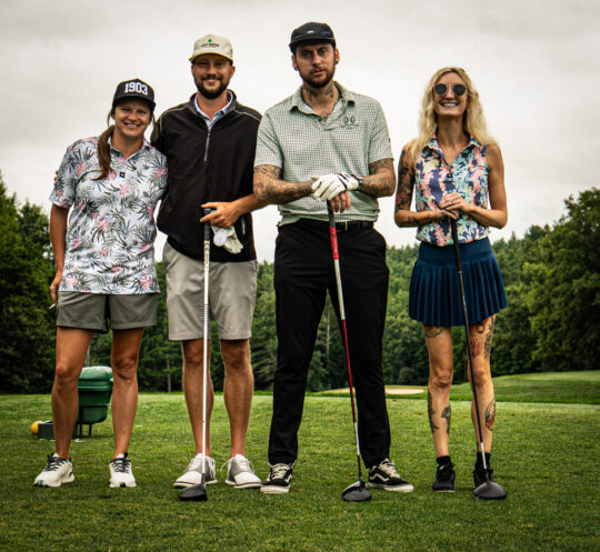 Portrait of golfers on a golf course holding golf clubs. Two men and two woman