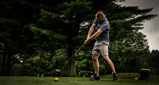 Golfer swinging with ball in air