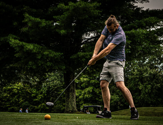 Golfer swinging with ball in air