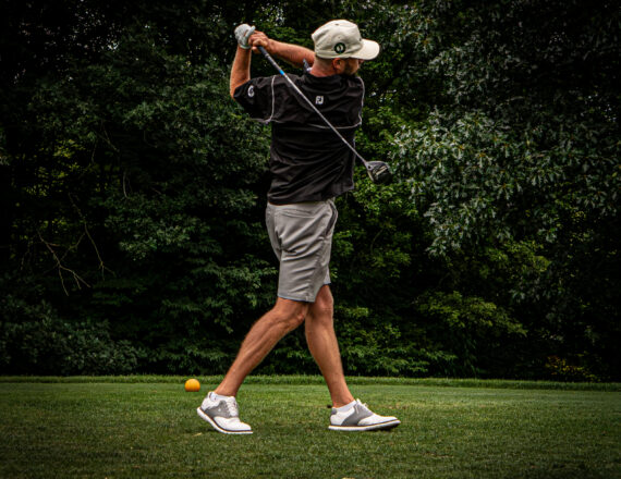 Portrait of a golfer on the follow through of hitting a golf ball on a golf course