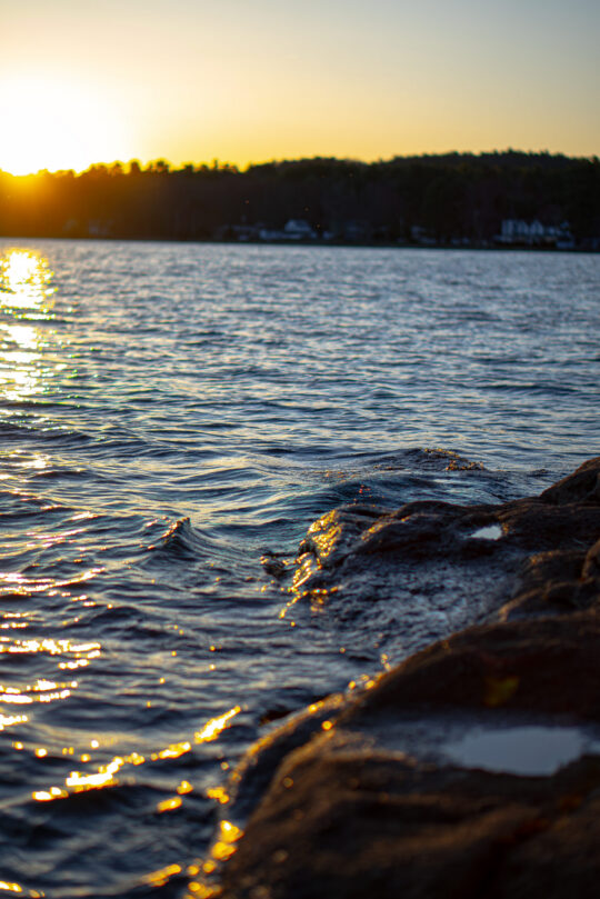 Sun set on a lake. water splashing onto the rocks